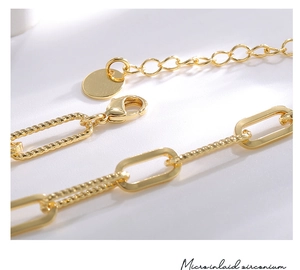 Vue macro d'une chaîne trombone plaquée or avec fermoir mousqueton et pendentif rond
