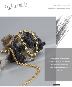 Close-up of golden beaded chain necklace wrapped on stone showing detailed craftsmanship