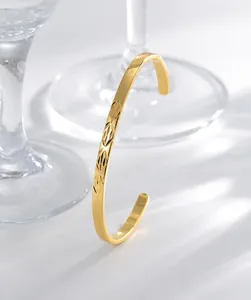 Detail of gold open cuff bracelet featuring geometric diamond-cut patterns and metallic luster