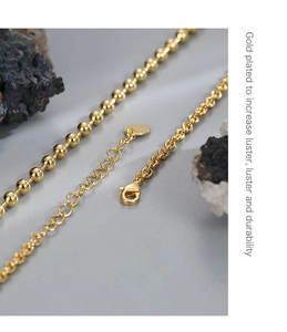 Close-up of gold-plated bead and link chain necklace with a secure lobster clasp
