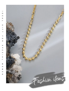 Detail of gold beaded chain necklace with rectangular links on elegant stone background