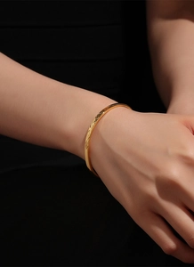 Detailed view of a slim gold bracelet with geometric diamond-cut patterns and polished finish