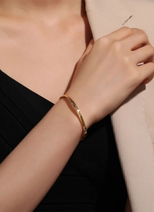 Close-up of a gold minimalist open bangle featuring intricate geometric diamond patterns