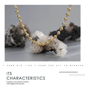 Macro shot of polished gold bead chain resting on a natural mineral stone backdrop