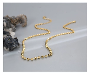 Macro view of gold beaded chain necklace with polished metal balls and link texture