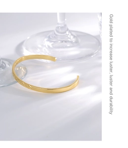 Detailed view of gold plated open bangle with floral engravings and elegant light shadows