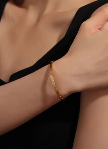 Detail of gold bangle showing intricate geometric floral engravings and polished finish