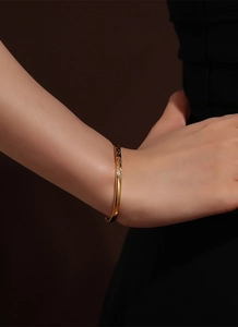 Detailed view of a gold bangle with geometric diamond patterns on a woman's wrist