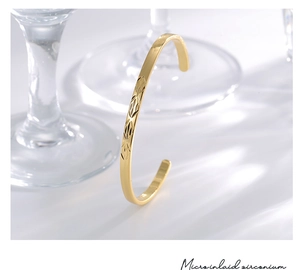 Detailed macro view of gold open bangle featuring intricate engraved geometric patterns