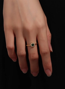 Macro view of gold-plated ring featuring an emerald-cut green stone and twisted band