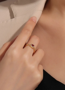 Close-up of gold ring featuring a rectangular red gemstone and white pavé setting