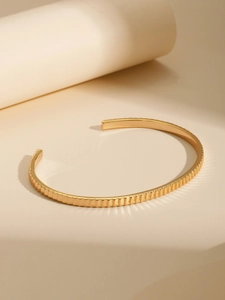Vista detallada del brazalete bañado en oro de 18K con textura de rayas verticales