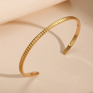 Brazalete rígido minimalista bañado en oro de 18K con textura de engranaje y abierto