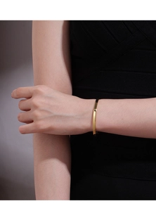 Gros plan d'un bracelet jonc doré minimaliste porté au poignet d'un mannequin
