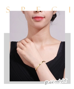 Vue rapprochée d'un bracelet ouvert doré poli minimaliste sur le poignet d'un mannequin