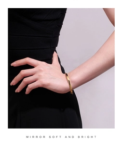Bracelet jonc doré poli sur le poignet d'un mannequin avec design épuré