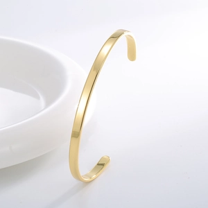 Bracelet jonc ouvert doré en forme de C avec finition miroir polie sur un plateau blanc