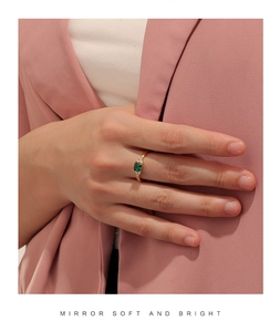 Dettaglio dell'anello da donna in oro con zircone verde quadrato indossato da una modella