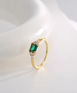 Dettaglio di un anello placcato oro con zircone verde taglio smeraldo e pietre bianche