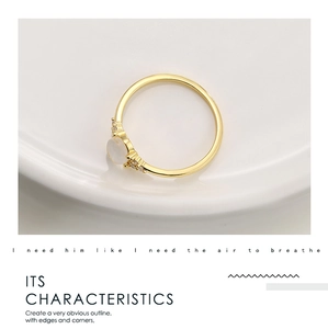 Close-up of elegant gold ring with moonstone and cubic zirconia accents on white background