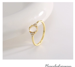 Close-up of golden ring with oval clear gemstone and micro-inlaid zirconium details