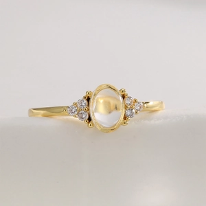 Vintage gold ring with oval moonstone and round zircon accents on a clean background