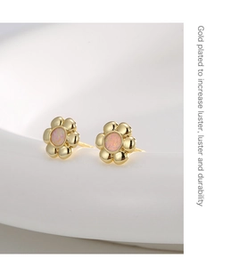 Detail of 18K gold plated flower earrings with pink opal center on white ceramic stand