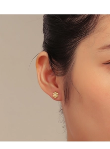 Detail of vintage 18K gold flower stud earring with white opal stone on a model ear
