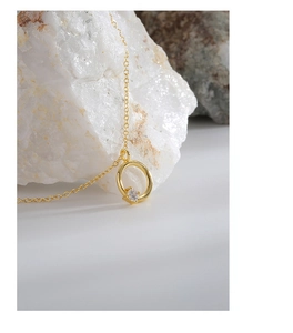 Detailaufnahme einer goldenen S925 Silberkette mit funkelndem Zirkon Anhänger auf einem Stein