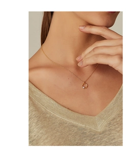 Nahaufnahme einer goldenen Halskette mit Zirkonia-Anhänger an einem weiblichen Model