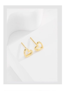 Macro shot of gold hollow heart-shaped S925 silver stud earrings on a geometric stand