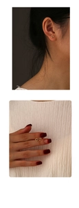 Detailed view showing minimalist hollow heart-shaped gold studs worn and held in hand