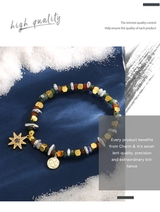 Dettaglio del bracciale con perline, ciondolo a stella dorata e moneta su seta