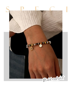 Primo piano del bracciale con perline con ciondolo a stella a otto punte e charm rotondo