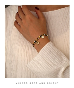 Dettaglio del bracciale di perline con ciondolo a stella e charms dorati sul polso