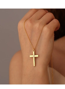 Detailansicht einer goldenen Kreuzkette mit kleinem Kristall, am Hals getragen