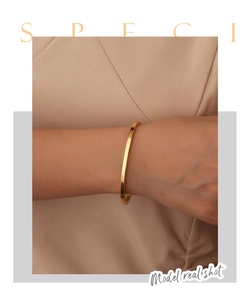 Detailaufnahme eines minimalistischen 18K vergoldeten Armreifs an einem Frauenarm