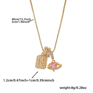 Detail of gold box chain with cubic zirconia N-letter square pendant and pink heart planet