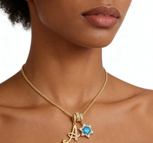 Close-up of 18K gold-plated snowflake pendant with blue gemstone and micro-pave letter A