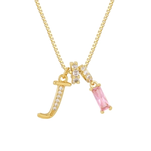 Detalle de collar chapado en oro 18K con letra J, gema rosa y anillo con circonitas