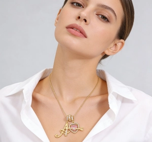 Detail of gold letter A pendant and pink enamel heart arrow necklace on model