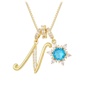 Macro detail of gold letter N pendant with blue zircon and snowflake crystal design