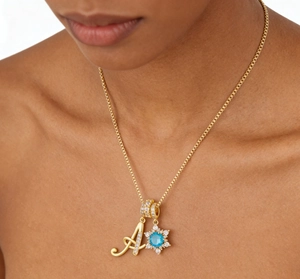 Gold necklace with letter A pendant and snowflake charm featuring a blue gemstone