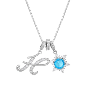 Macro shot of silver letter H necklace with snowflake pendant and blue zircon stone