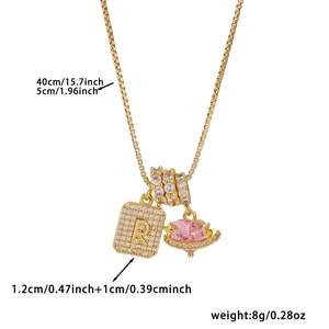 Detail view of gold box chain necklace with zircon letter R and pink heart planet pendant