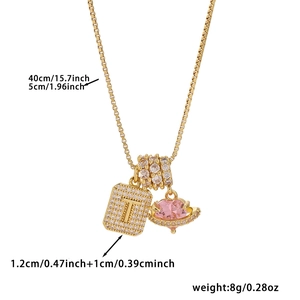 Macro detail of 18K gold plated necklace with cubic zirconia T-pendant and pink heart saturn