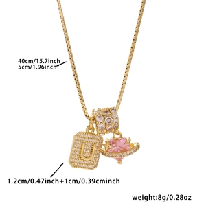 Detail of gold box chain necklace with zircon letter U and pink heart gemstone pendant