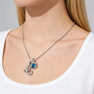 Detailed view of silver necklace with blue gemstone pendant and crystal letter L on neck