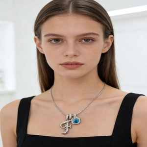 Macro view of silver necklace with diamond-set letter F and square blue gemstone