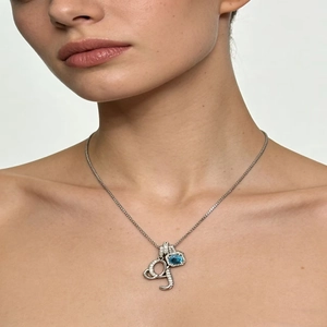 Close-up of a silver letter pendant necklace with a teardrop blue stone on the collarbone